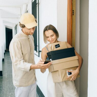 A man and woman engaged in a home delivery package exchange, smiling.